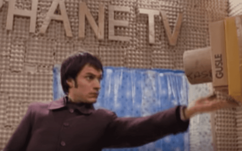 A man looking at a cardboard camera.