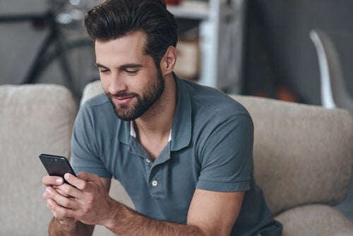 A man reading something pleasant on his phone.