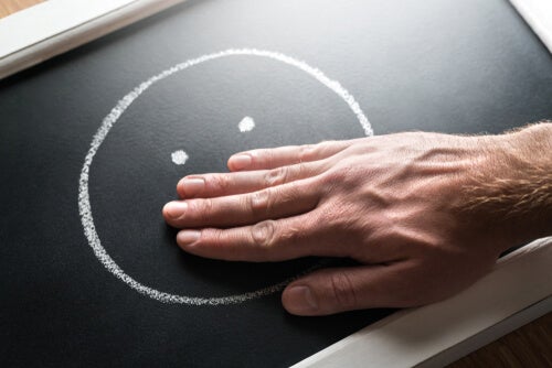 A person covering the smile of a smiley.