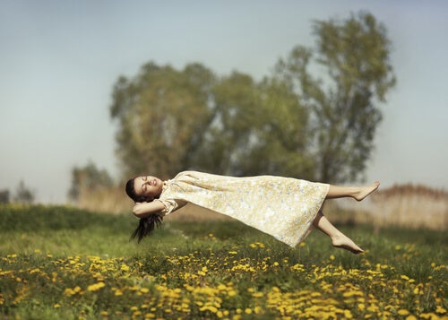 A woman floating above a field.