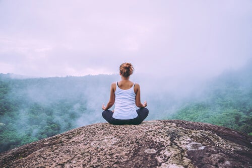 A woman meditating on top of a mountain.