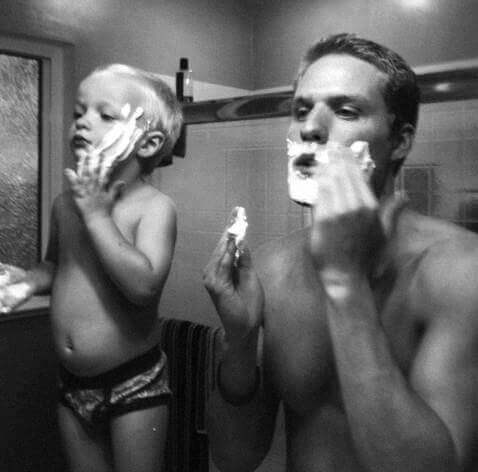 Father and son applying shaving cream.