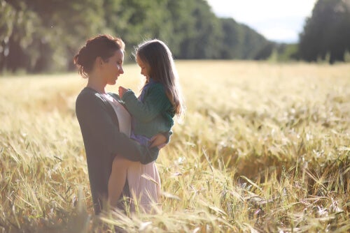 Mother holding daughter in a field.