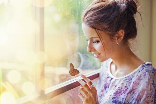 A woman smiling at a butterfly on the window.