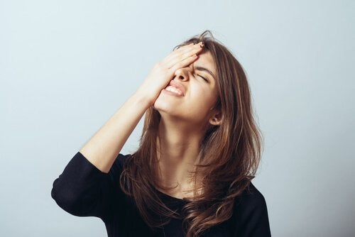 A woman holding her head because she forgot something.