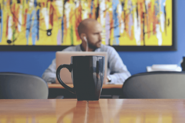 Mug in the foreground and man in the background.