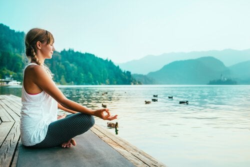 A woman meditating by the water.