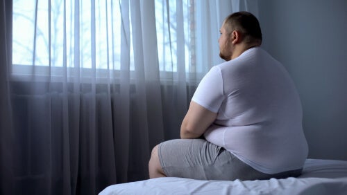 An obese man sitting on a bed.