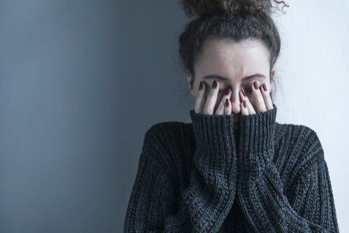 A woman covering her face with her hands.