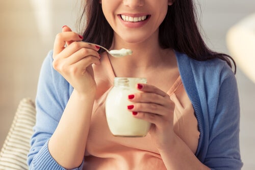 A woman eating a yogurt who looks happy. which is what neurogastronomy is interested in.