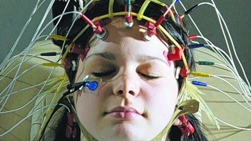 A woman with electrodes attached to her head engaging in sleep learning.