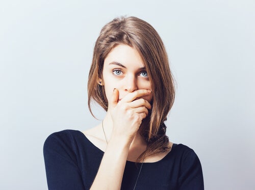 A woman covering her mouth symbolizing self-censorship.