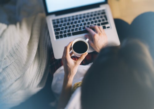 A woman drinking coffee and working on her computer.