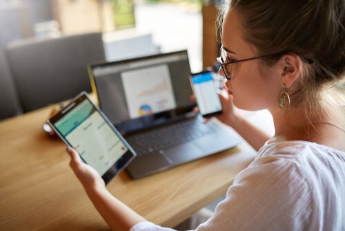 A woman with three electronic devices.