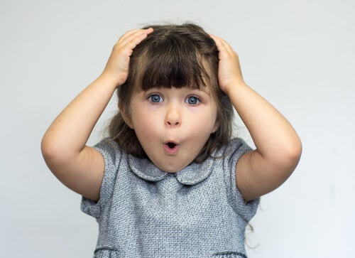 A little girl with her hands on her head, looking surprised.