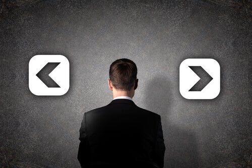 A man looking at a wall with two opposite arrows.