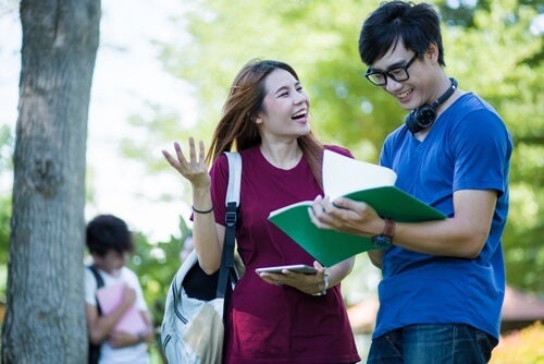 Two students talking and laughing outside.