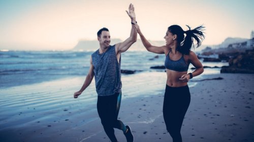 A man and woman high-fiving each other while jogging.