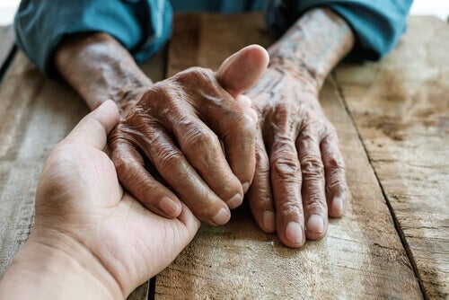 An old person's hand holding a younger person's hand.