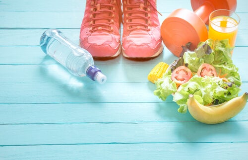 Healthy food, tennis shoes, a dumbbell, and a bottle of water on a blue floor.