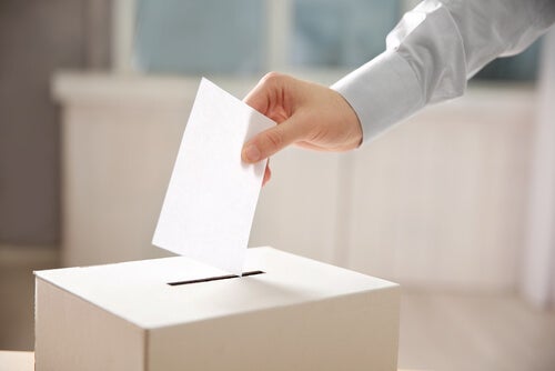 A person who follows populism putting their vote inside a box.