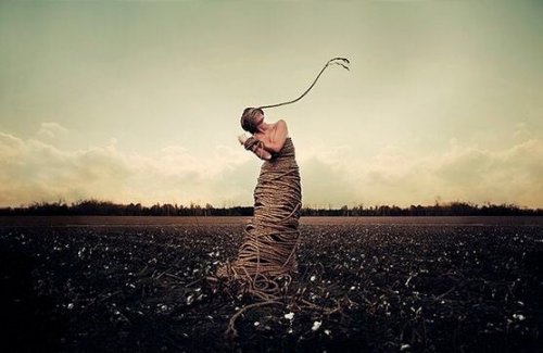 A woman in a field tied up with rope.