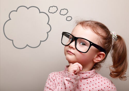 A young girl with glasses with a thought bubble drawn on the wall next to her.