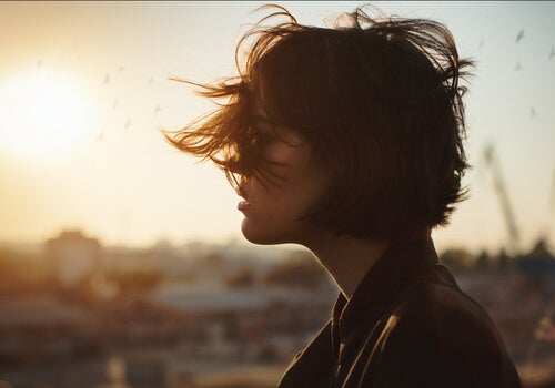 A woman whose hair is being blown about by the wind.