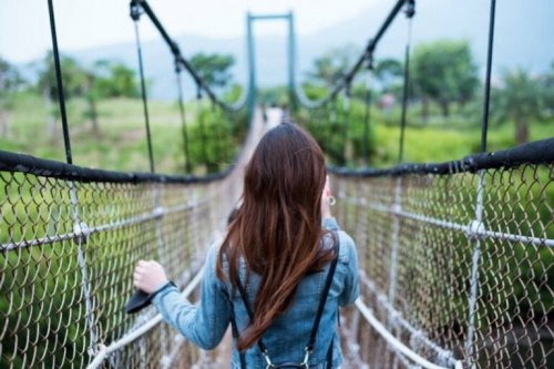 A woman crossing a bridge, taking steps to improve her well-being.