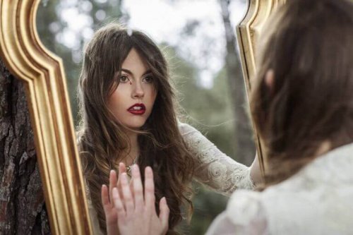 A woman looking at herself in a mirror in the woods.