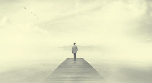 A person walking on a pier in the fog.