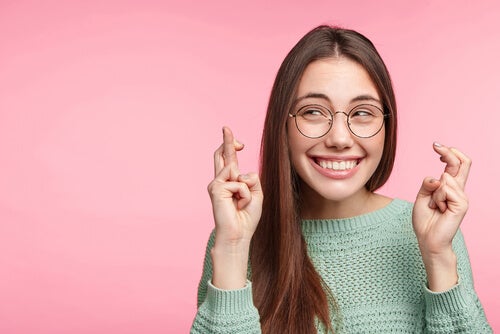 A woman smiling and crossing her fingers.