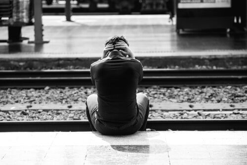 A boy sitting by train tracks.