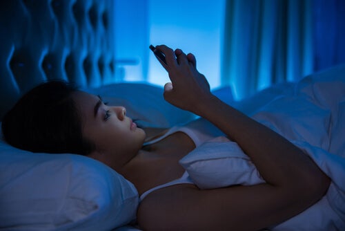 A woman using her phone in bed.