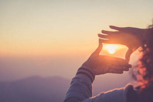 A woman framing the sun with her hands.