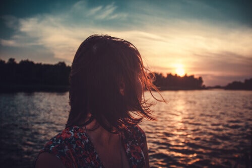 A woman looking at at the sunset on a lake.