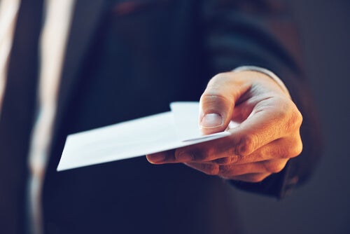 A person handing out an envelope.