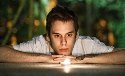 A man looking directly into a small lightbulb.