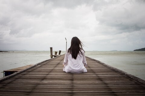 A woman sitting on a pier by the ocean.