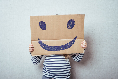 A child behind a smiley face board.