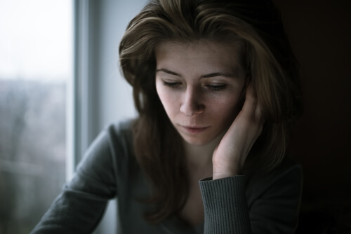 A sad woman looking down finding it hard to ask for help.
