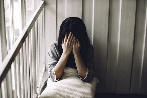 A woman with her hands over her face.