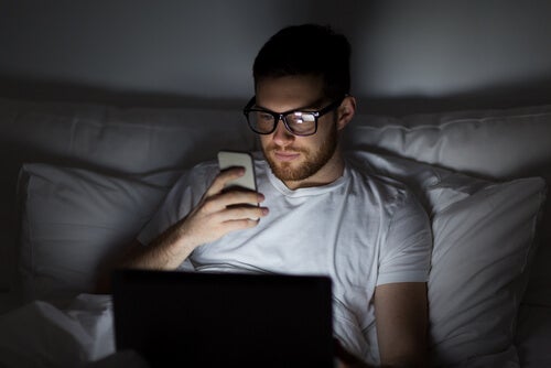 A man looking at his phone in bed.
