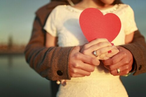 A couple holding a red paper heart.
