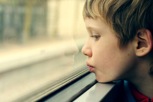 An autistic kid looking out of a window.