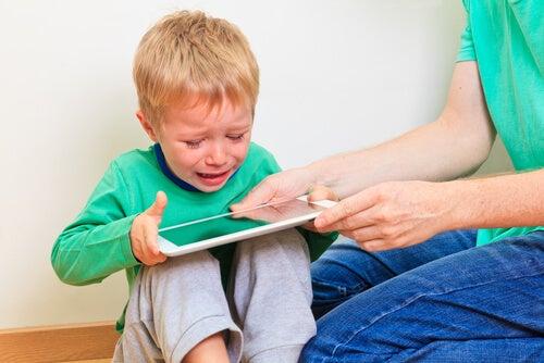 A parent giving their child a tablet so that they stop crying.