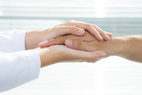 A doctor holding a patient's hands, representing universal health coverage.