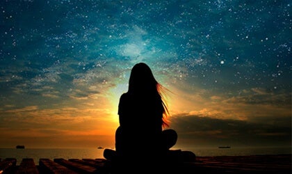 En kvinne som ser på en stjernehimmel.