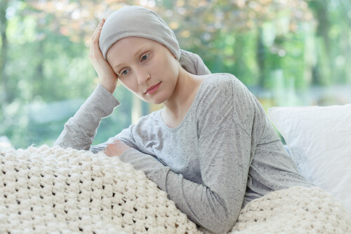 A woman with gynecologic cancer sitting on a couch with a head wrap.