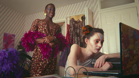 A woman in front of a computer and a man behind her.